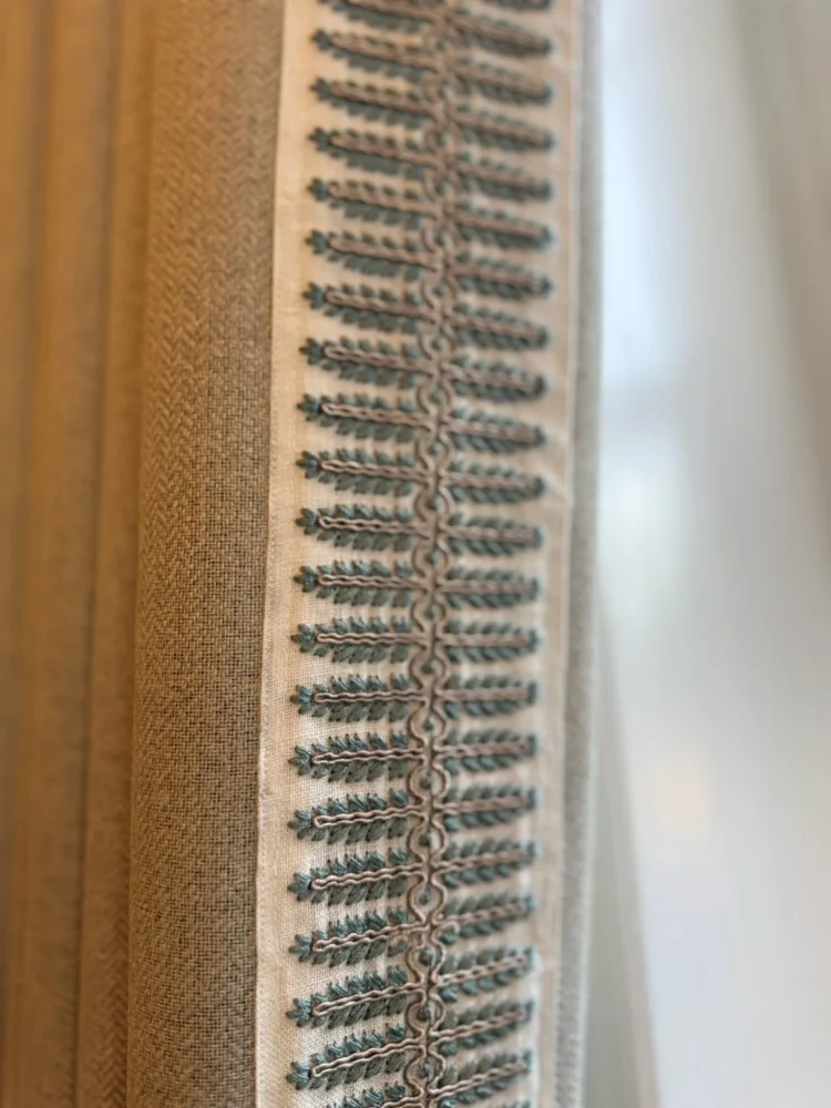 Close-up of a woven braid trim sewn along the leading edge of a neutral curtain