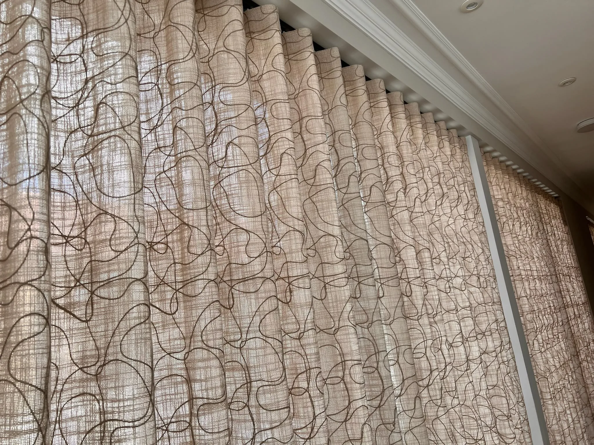 Sheer wave curtains in a looped line print running along a wall of windows