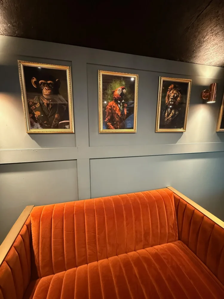 Channel-stitched burnt-orange velvet banquette beneath framed portraits on a panelled wall