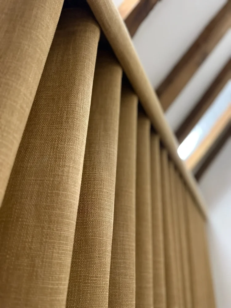 Close-up of mustard linen-look wave curtain folds, lit from the side