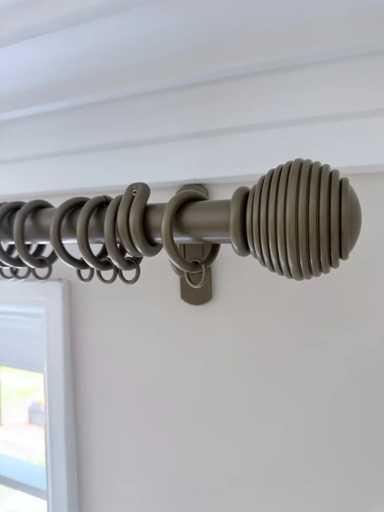 Metal curtain pole with a ribbed ball finial, rings and a bracket