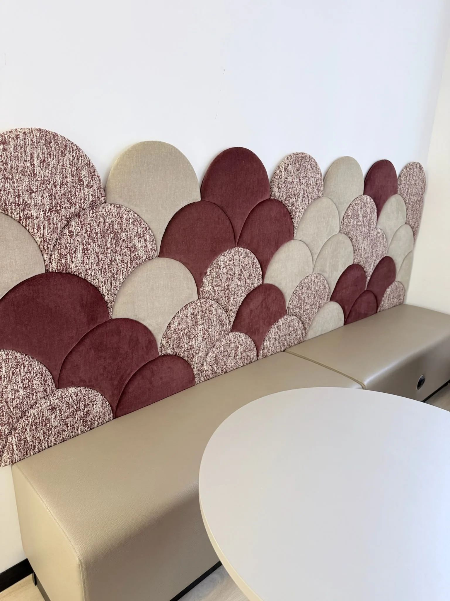 Scalloped upholstered wall panels in burgundy, cream and speckled fabrics above a fitted bench seat