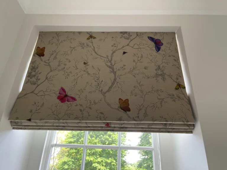Roman blind in a branch and butterfly print, raised in a sash window recess