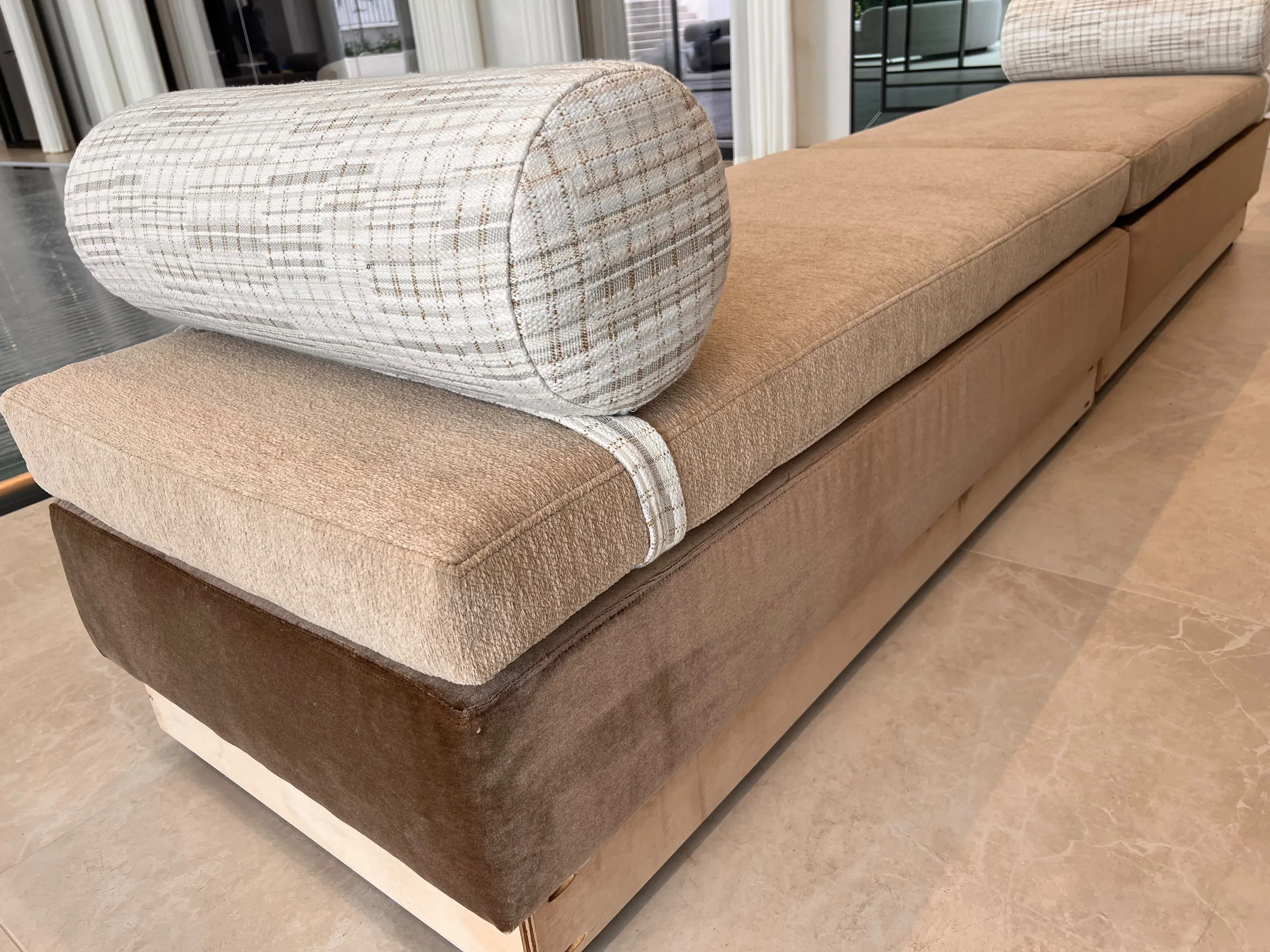 Long upholstered bench seat in caramel velvet with a checked bolster cushion