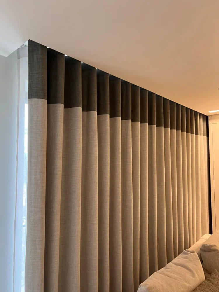 Floor-to-ceiling grey wave curtains with a lighter lower band, along a wall of windows