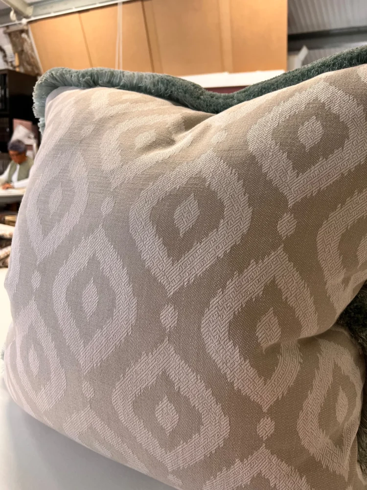 Close-up of an ikat-pattern cushion with a soft teal fringed edge