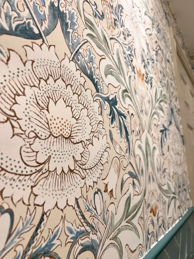 Close-up of a blue and orange botanical wallpaper above sage tiles