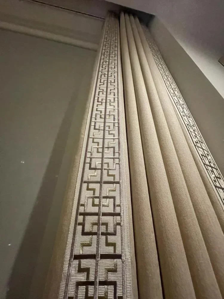 Looking up a neutral wave curtain with a Greek key border on the leading edge