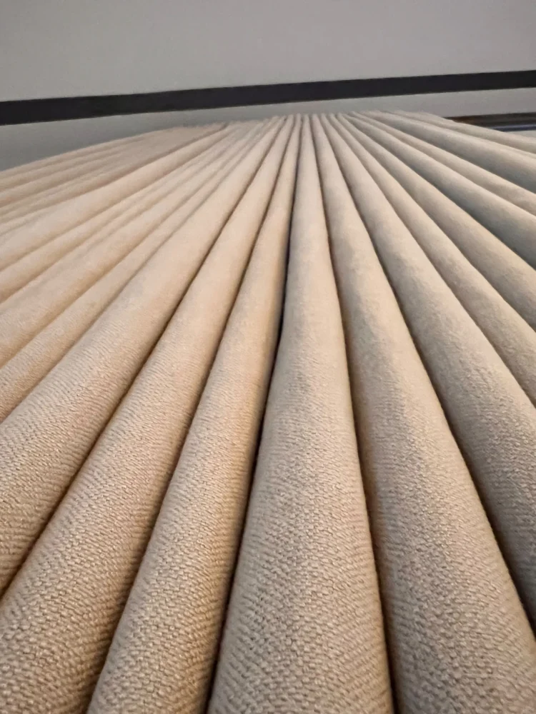 Looking down the regular folds of a neutral textured curtain stack