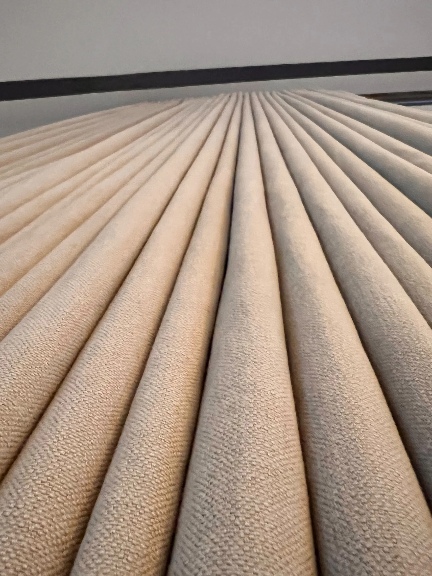 Looking down the regular folds of a neutral textured curtain stack
