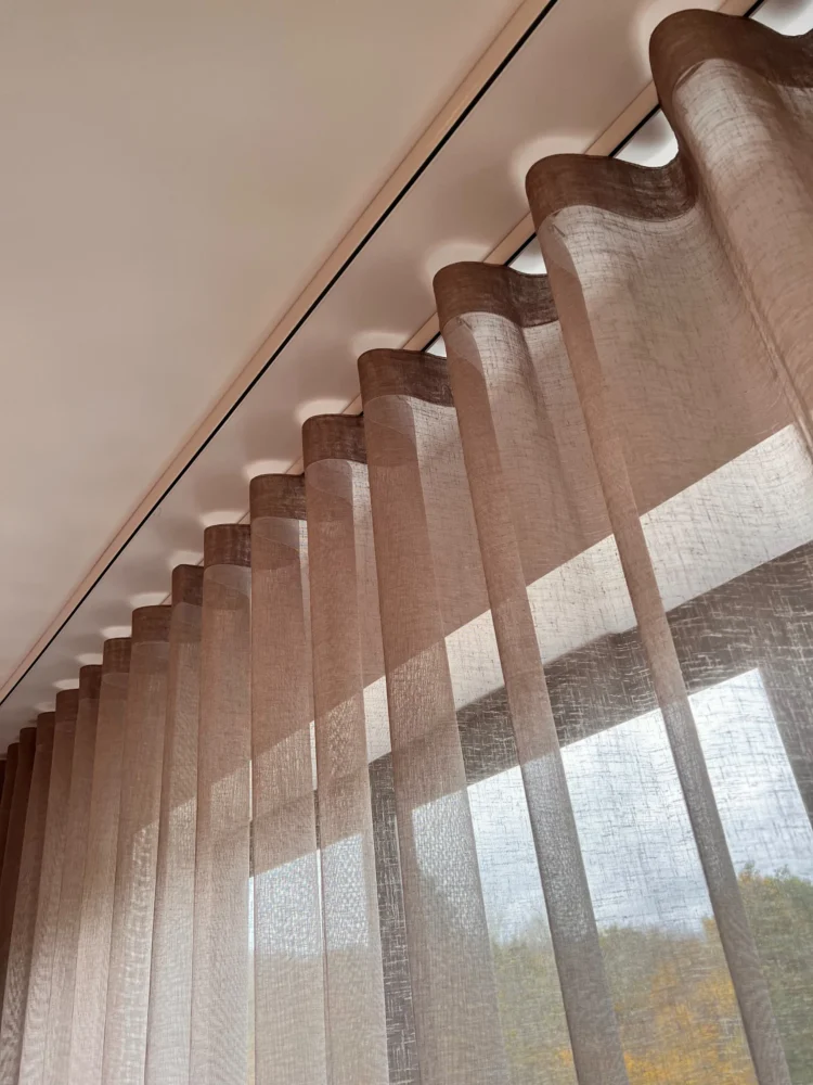 Sheer wave voile on a ceiling track, seen from below against a window