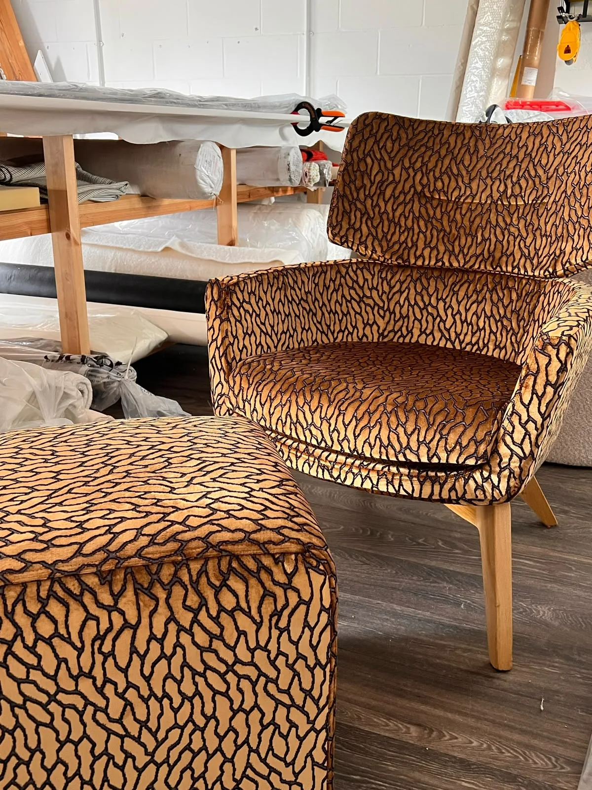 Matching armchair and cube footstool in amber and black animal-pattern velvet, in the workroom