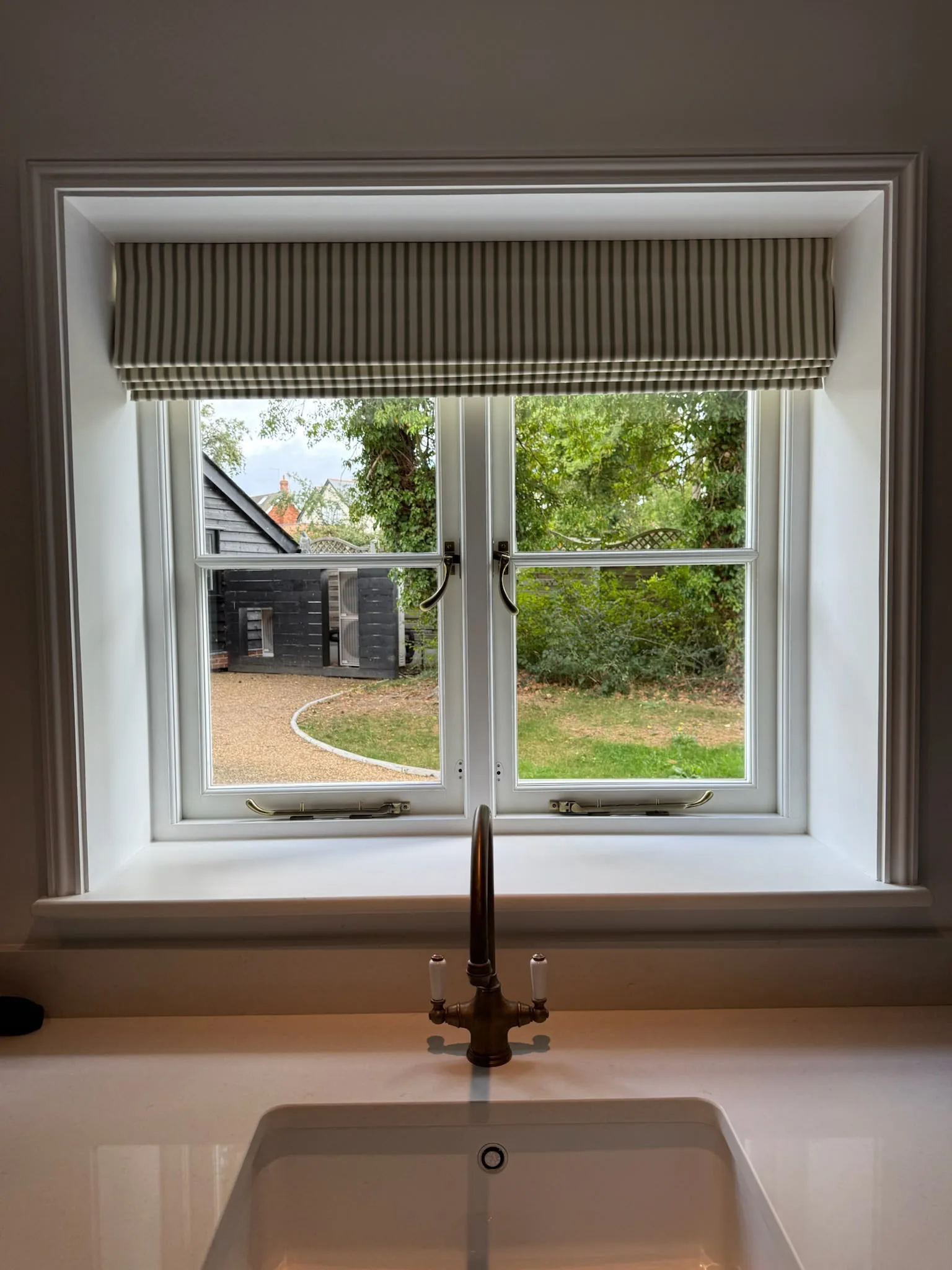 Striped Roman blind in a deep window recess above a kitchen sink