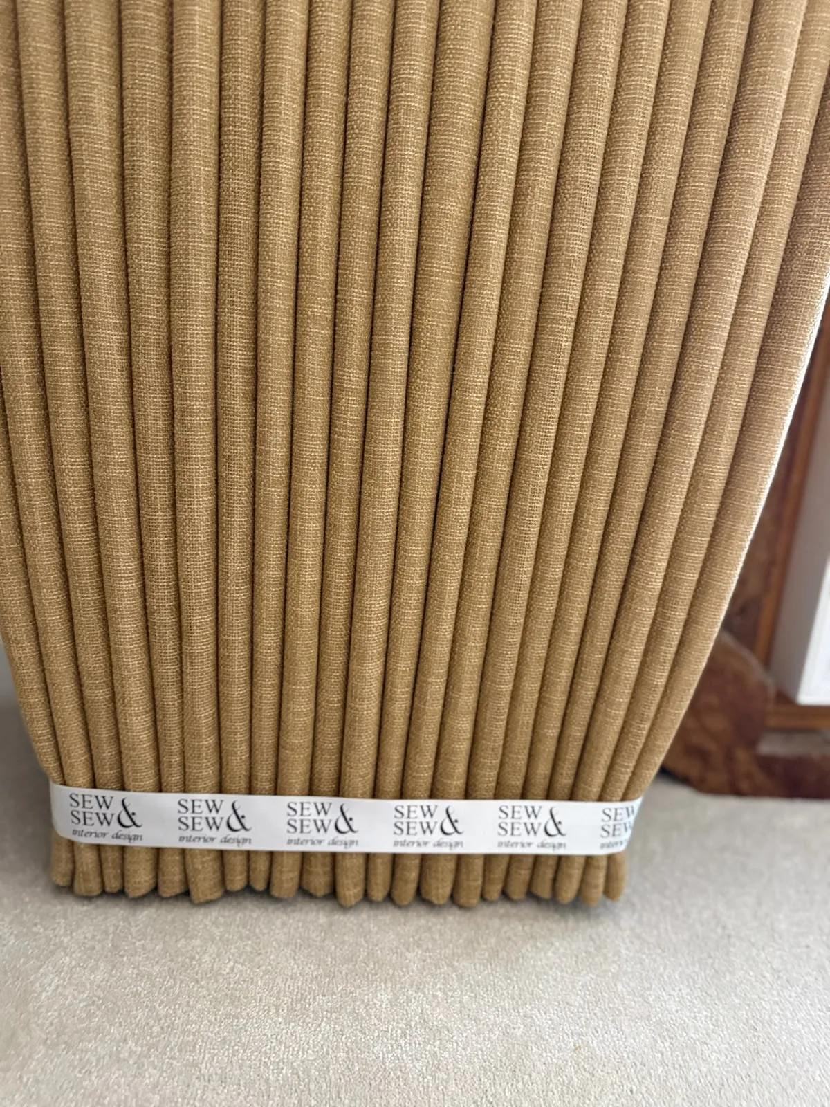 Mustard linen-look curtain gathered at the hem with a Sew & Sew branded band, before dressing