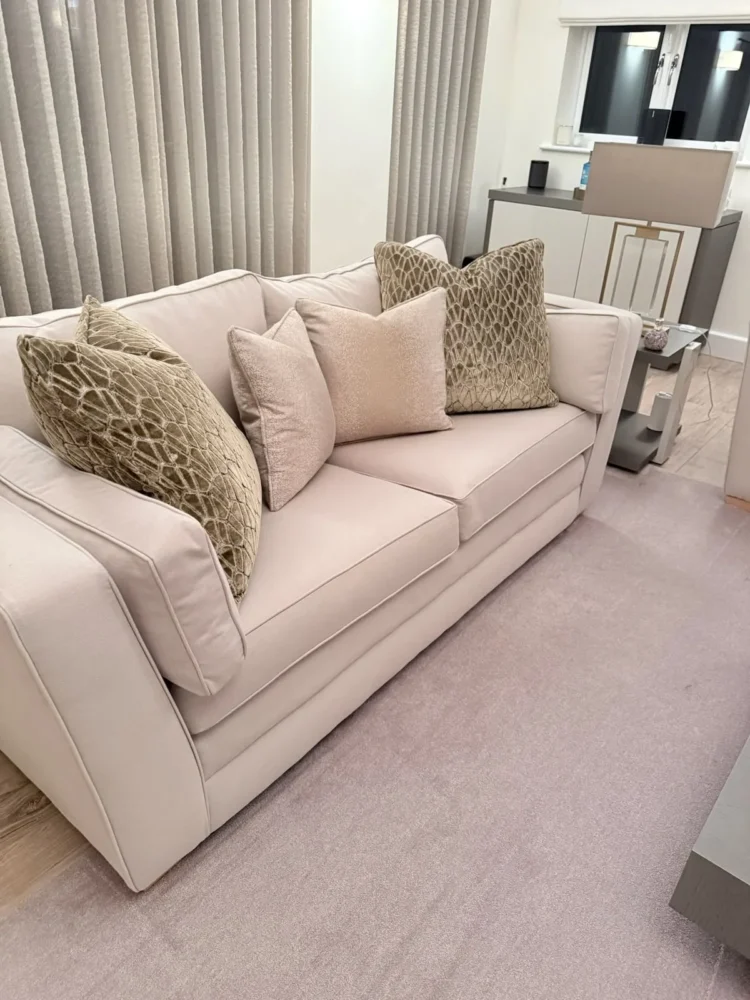 Cream sofa with geometric-pattern scatter cushions in front of grey wave curtains
