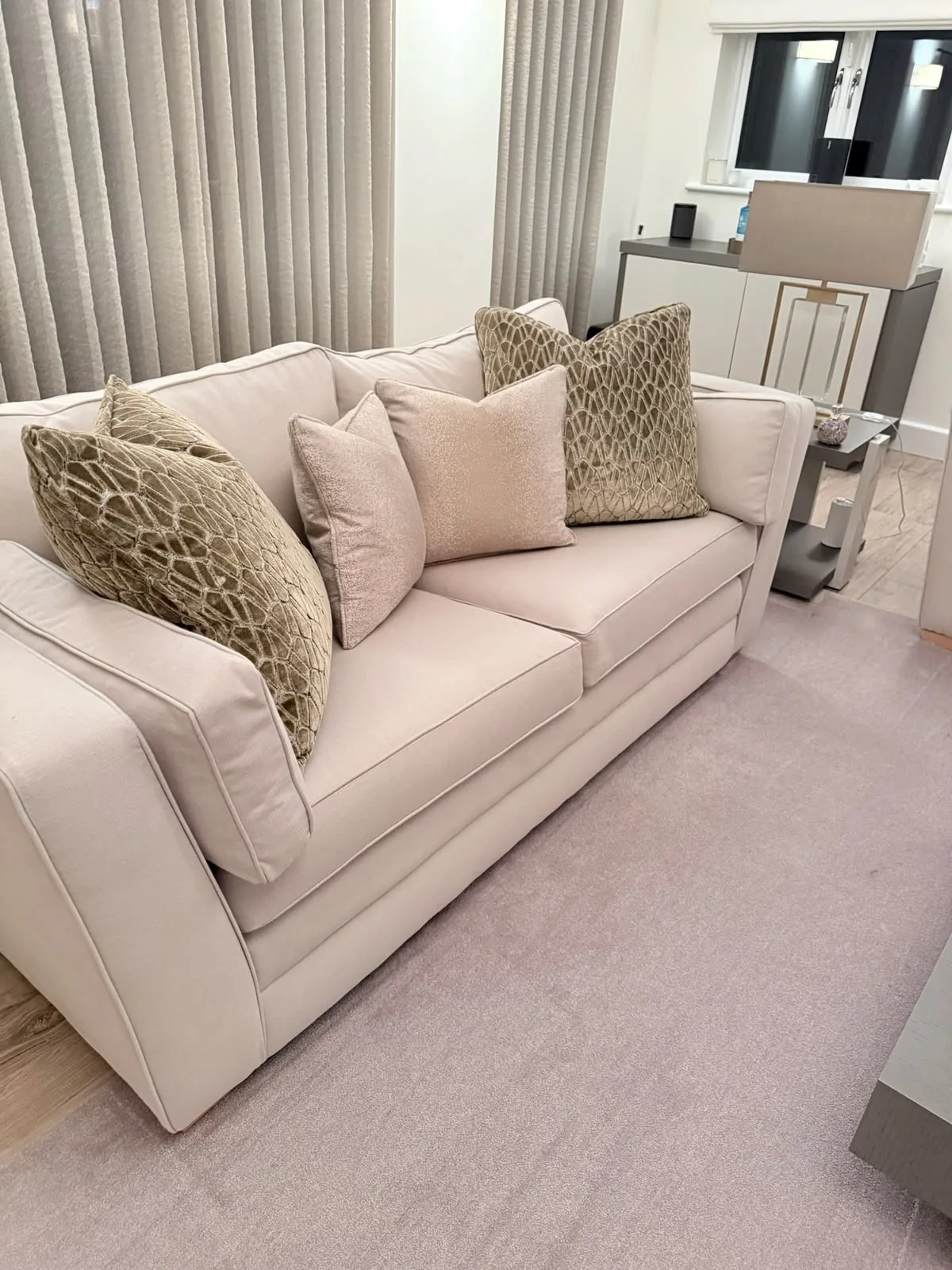 Cream sofa with geometric-pattern scatter cushions in front of grey wave curtains