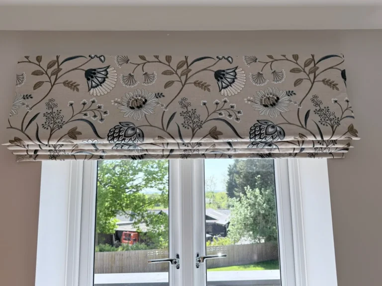 Roman blind in an embroidered-look botanical print, raised above French doors overlooking a garden