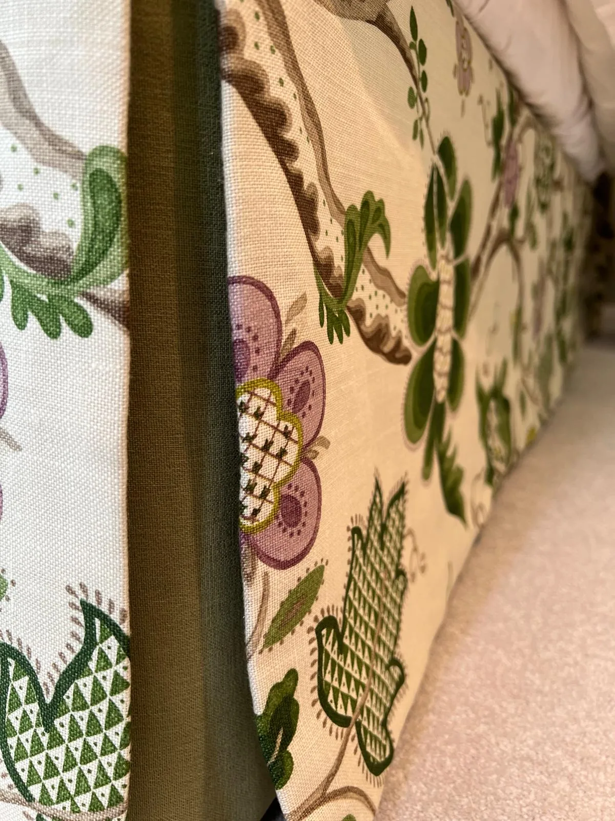 Close-up of the inverted pleat at the corner of a floral crewel-style bed valance