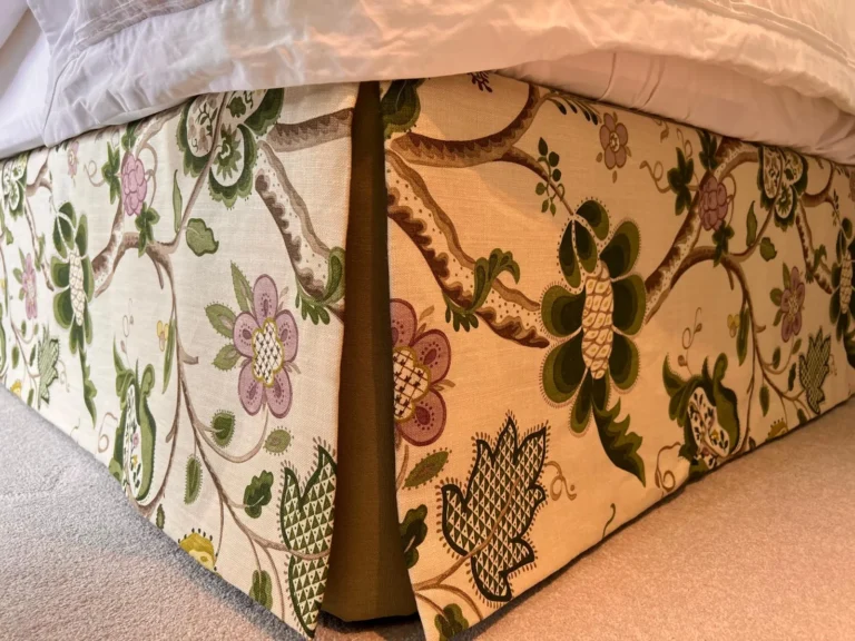 Floral crewel-style bed valance with a plain green inverted corner pleat