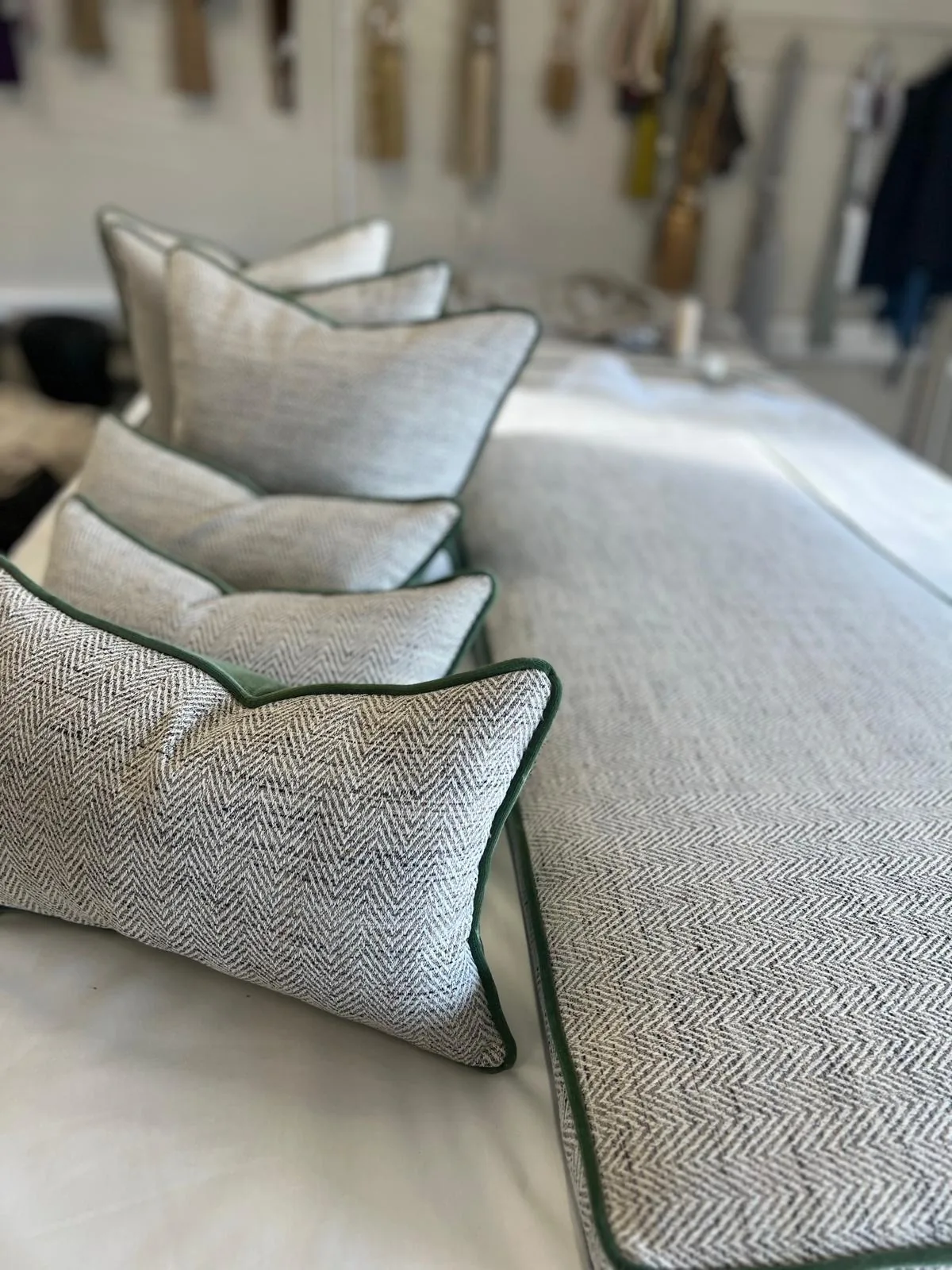 Row of herringbone cushions with green piping on the workroom table