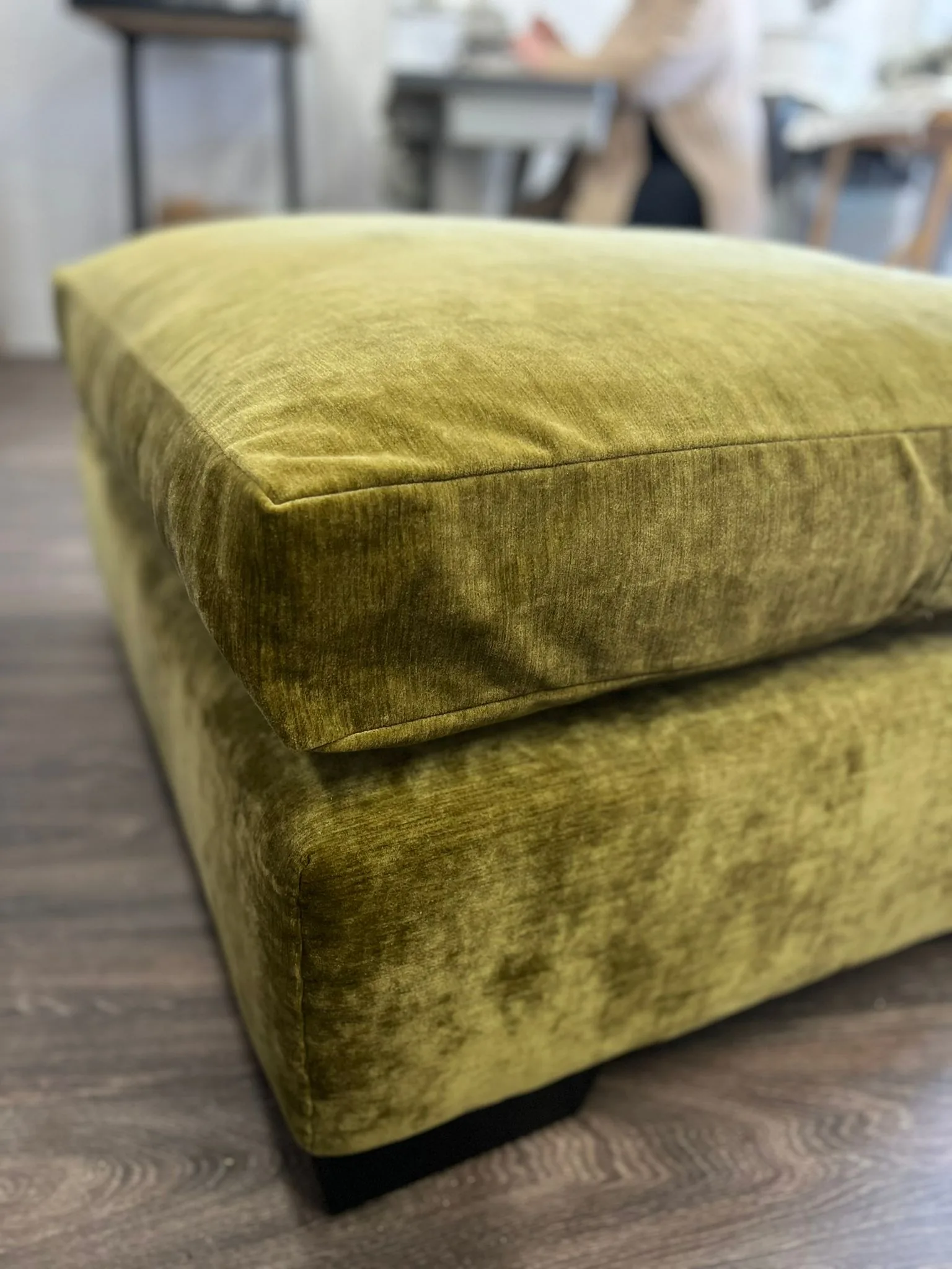 Close-up of a footstool upholstered in chartreuse crushed velvet with piped edges