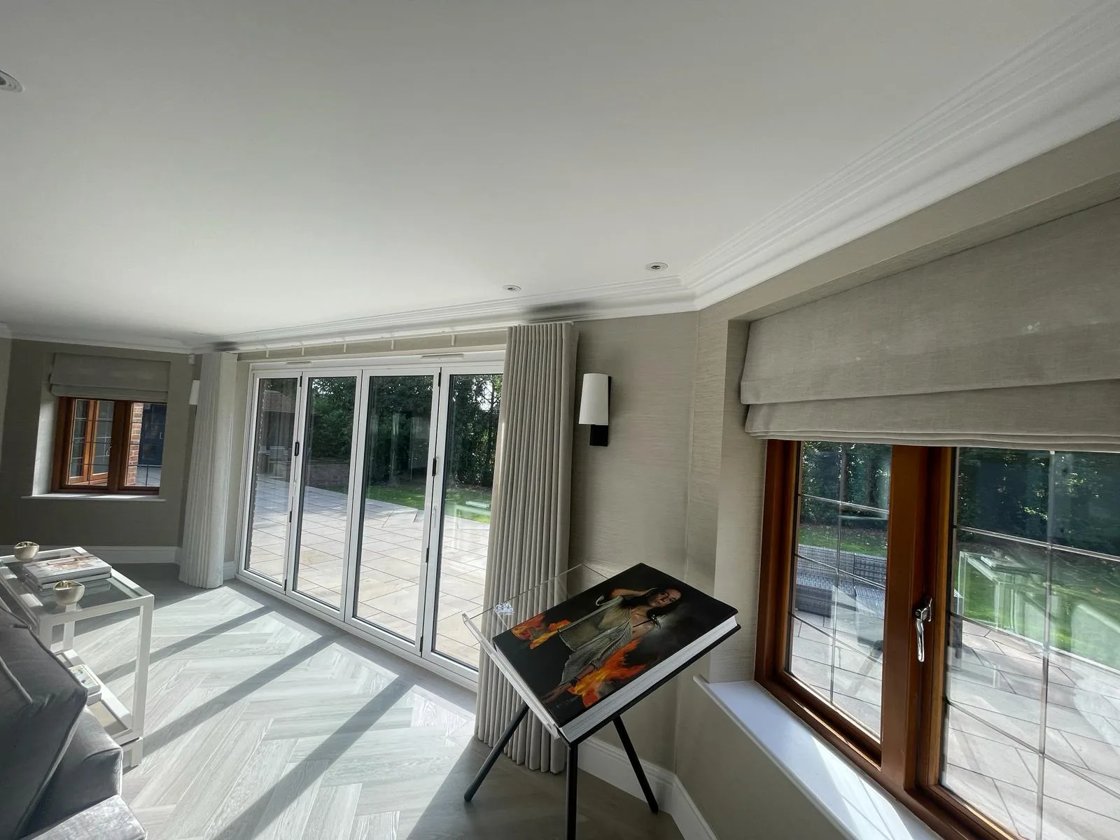 Room with a neutral wave curtain at sliding doors and a Roman blind over a second window