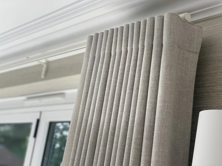 Close-up of a textured neutral wave curtain on a ceiling track below a cornice