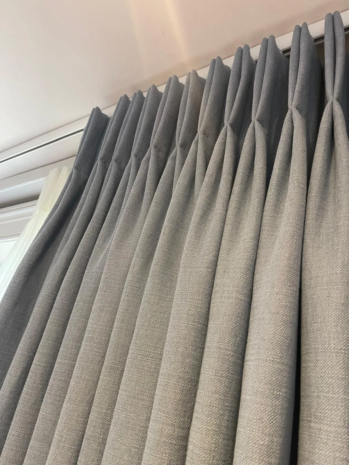 Looking up at blue-grey pinch-pleat curtains on a ceiling track