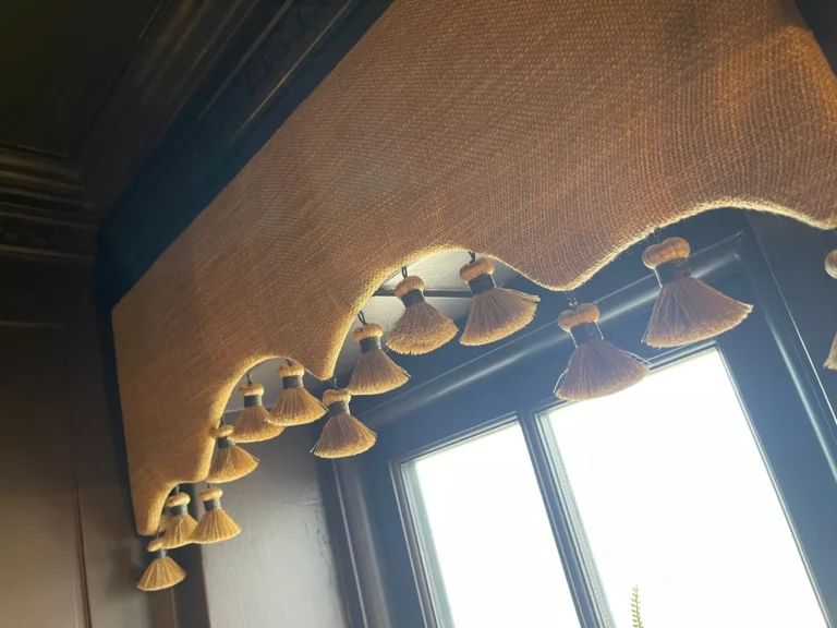 Shaped textured pelmet edged with a tassel fringe, above a backlit window