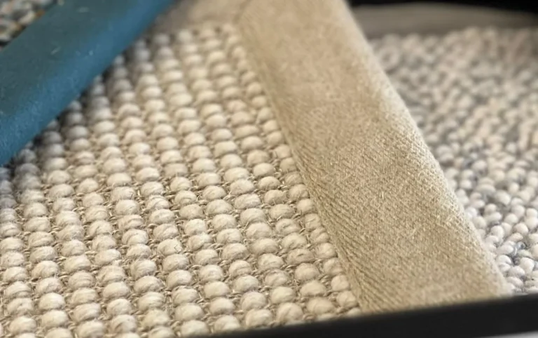 Close-up of a natural woven rug sample with a teal bound edge